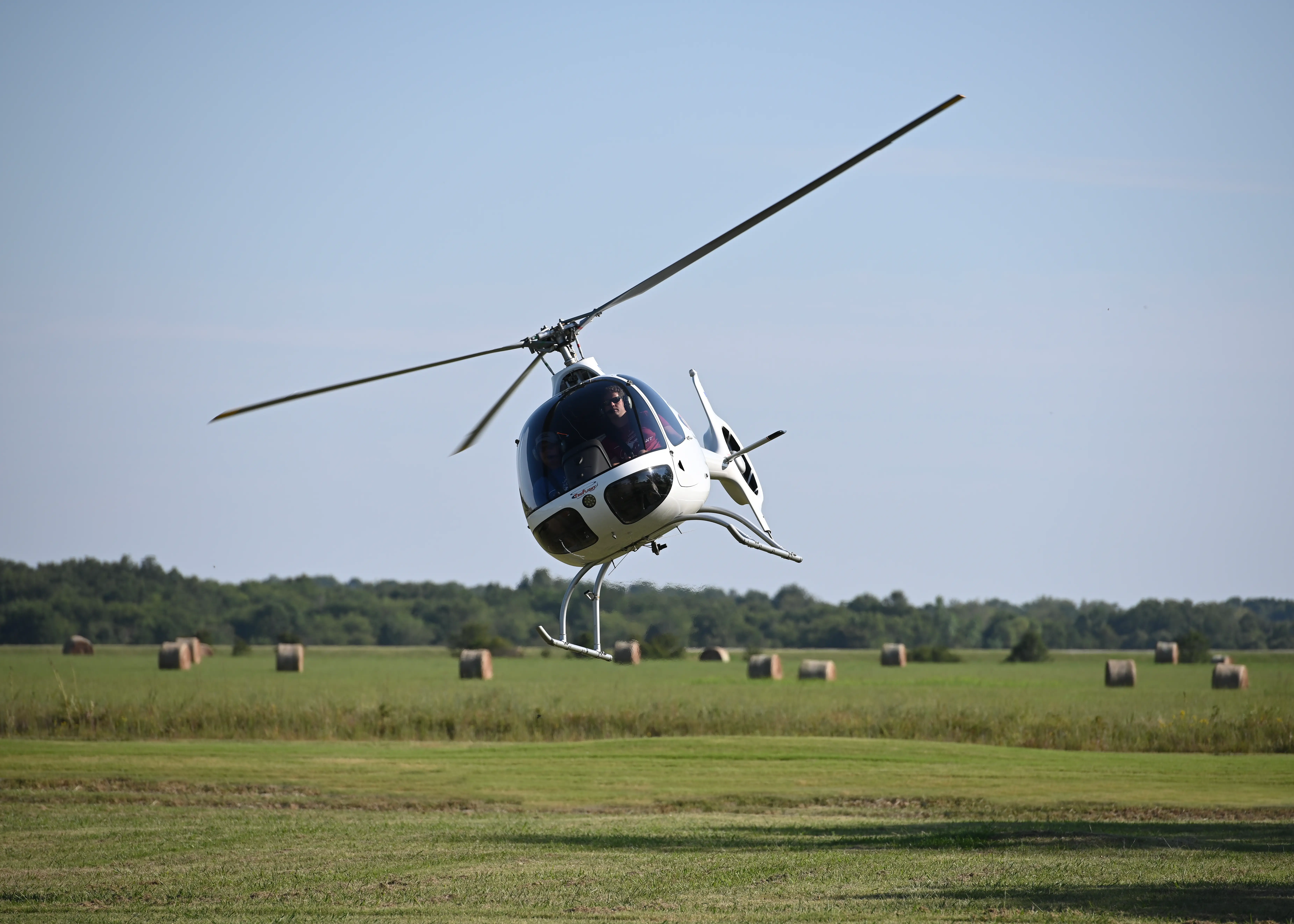 Front view from the ground of helicopter flying over a field