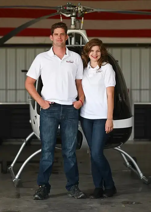 Scarlett and Todd Guison in front of a helicopter